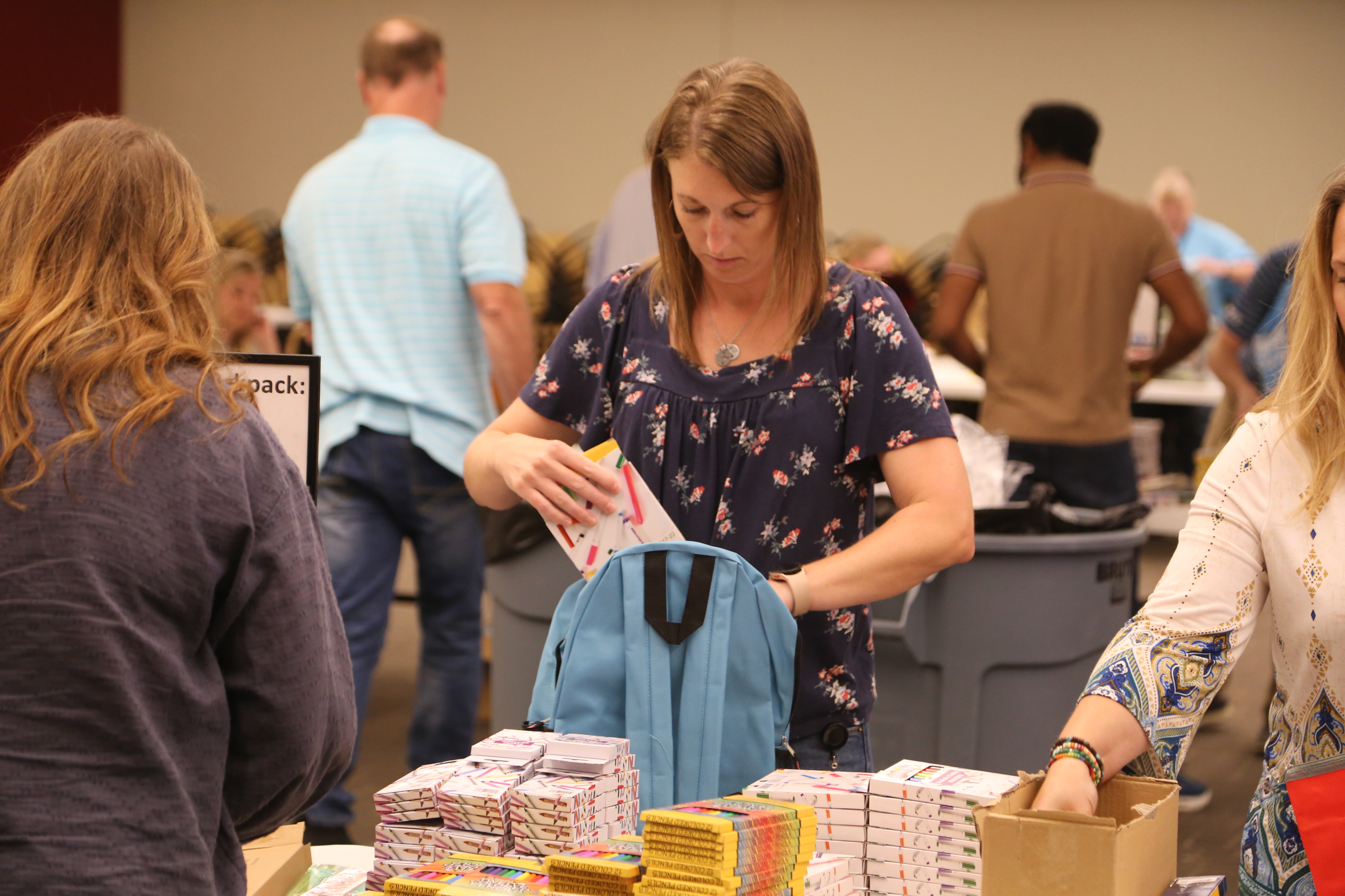 Post Consumer Brands employee filling backpack with donated school supplies