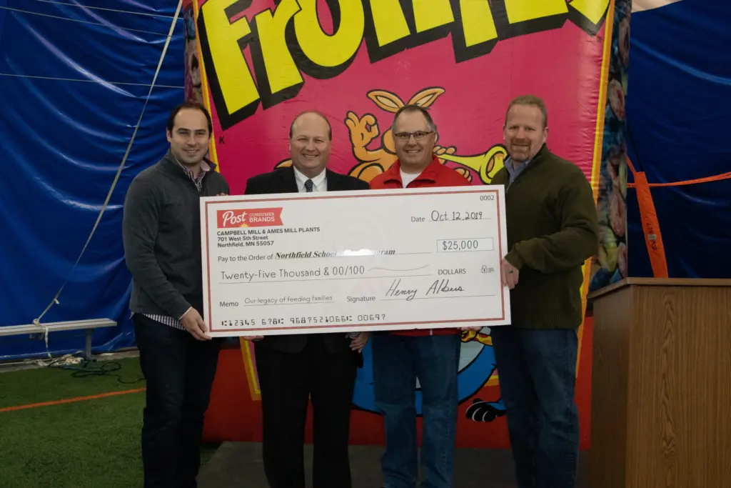 Group of four men standing with donation check
