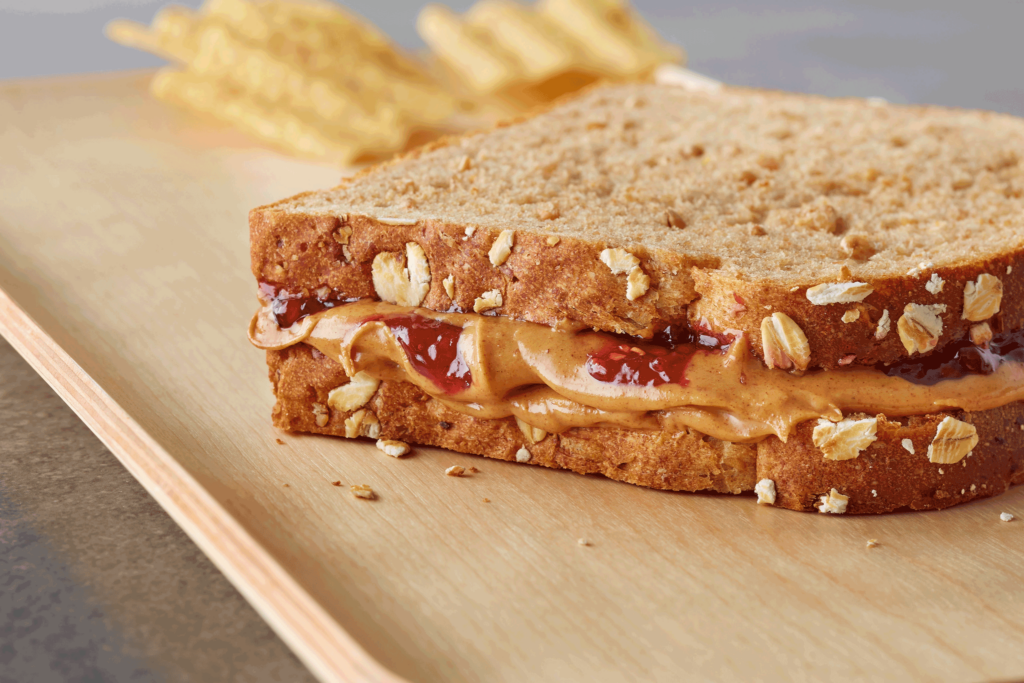 A peanut butter and jelly sandwich with chips in the background.